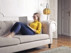 A woman works on the couch in a furnished apartment
