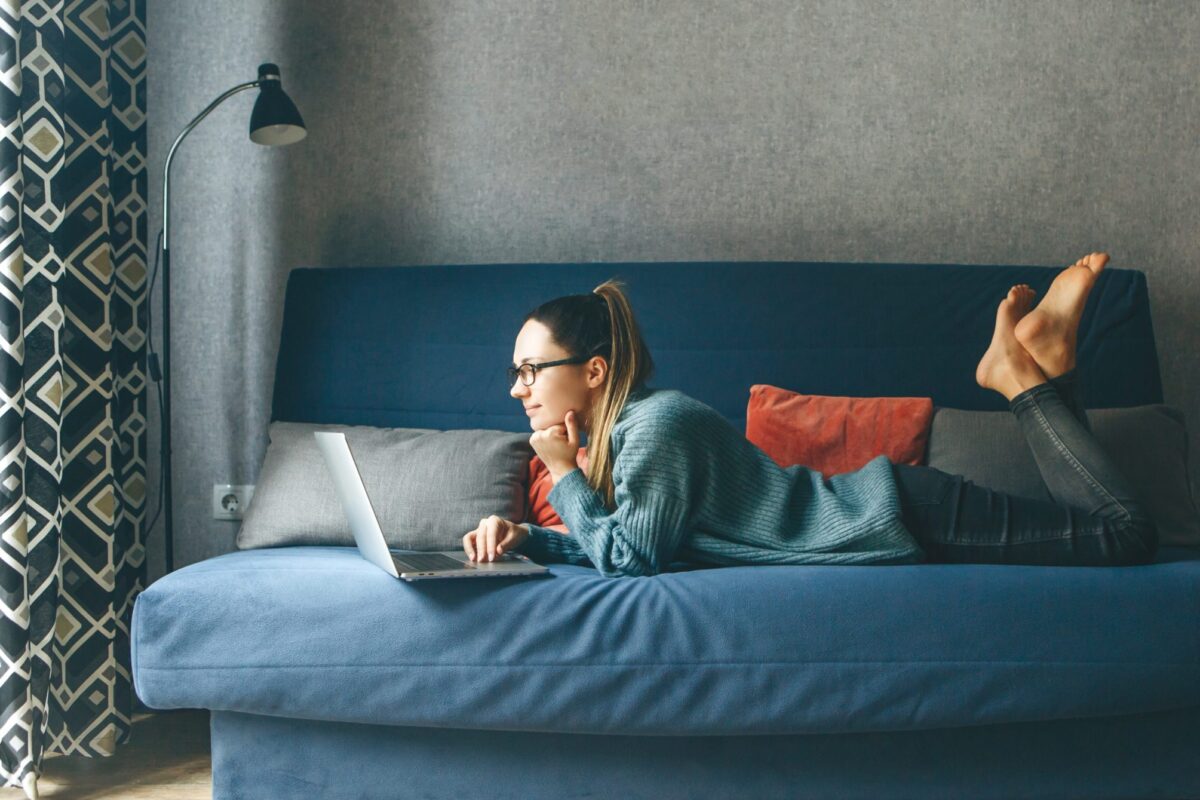 Woman lounging on the couch researching how to rent an apartment.