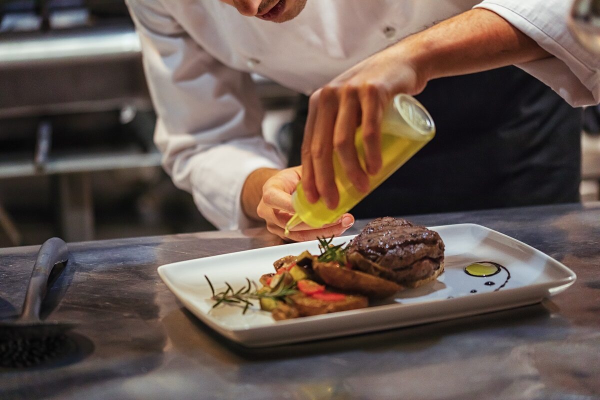 Chef in restaurant in Jacksonville rearranges and decorates food.