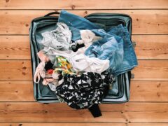 Packing suitcase with clothes before moving into a landing