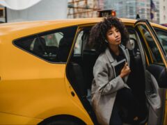 Woman getting out of a yellow New York City in cab in the Murray Hill neighborhood of New York City.