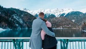 Couple hugging on winter vacation and looking at snow-covered mountains.