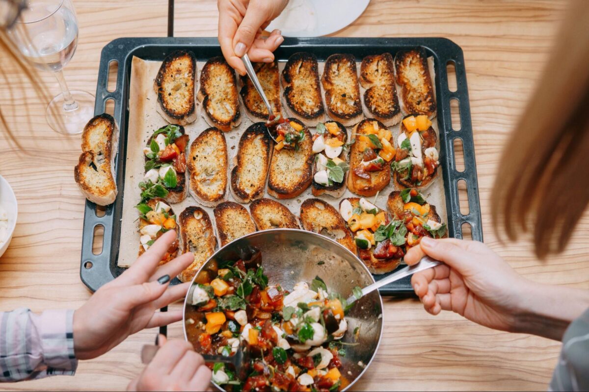 Group makes bruschetta on a table as part of an experience holiday gift