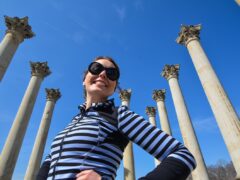 Smiling young woman poses in front of the Capitol Columns at the National Arboretum in Washington, D.C.