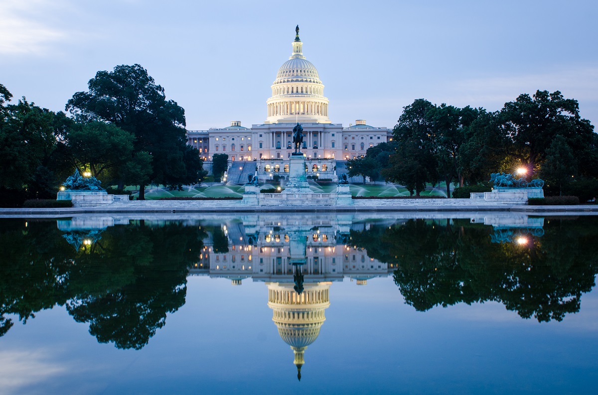 The U.S. Capitol Building in Washington, D.C., in a cloudy sunrise with mirror reflection.