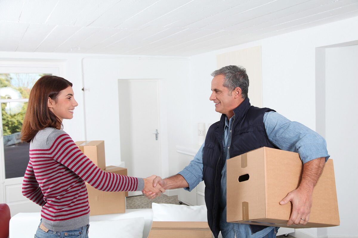 Woman shaking hands with professional mover after giving movers a tip.
