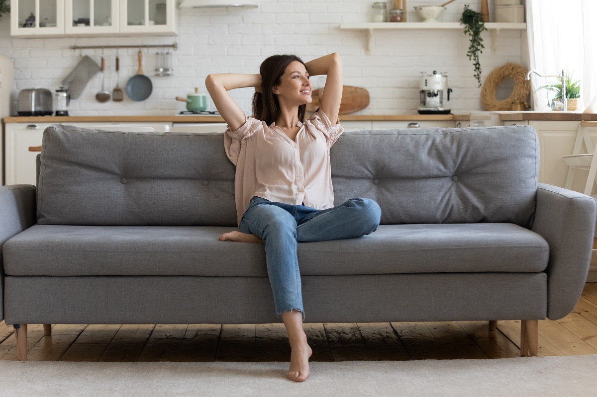 Woman sitting on couch in cozy living room in her apartment.