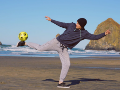 Max Hilty balances a soccer ball on his foot on the beach.