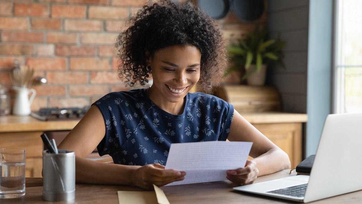 Happy young woman reading reference letter for an apartment on a piece of paper.