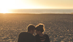Dating digital nomads embrace on a beautiful beach.