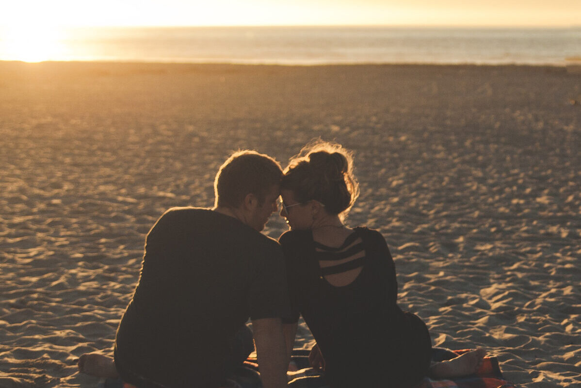 Dating digital nomads embrace on a beautiful beach.