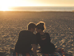 Dating digital nomads embrace on a beautiful beach.