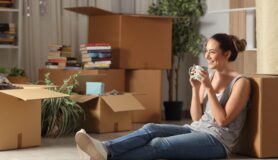 Woman sits in her new apartment surrounded by moving boxes