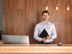 Concierge stands behind a desk in an apartment building.