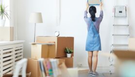 Woman takes down picture from off the wall while packing up and moving.