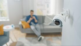 Man sits in his apartment with a security camera