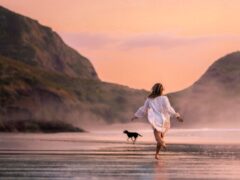 Woman travels alone in the U.S. and explores a beach with her dog.