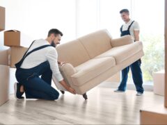 Two movers from a professional moving services company help move a couch.