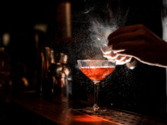 A bartender creates a delicious cocktail drink at a bar serving the best cocktails in Dallas.