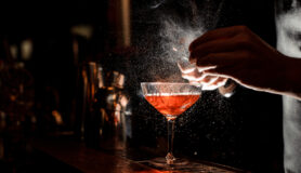 A bartender creates a delicious cocktail drink at a bar serving the best cocktails in Dallas.