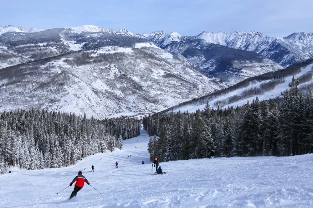 People alpine downhill skiing on trail at Vail ski resort in the Colorado Rocky Mountains in winter