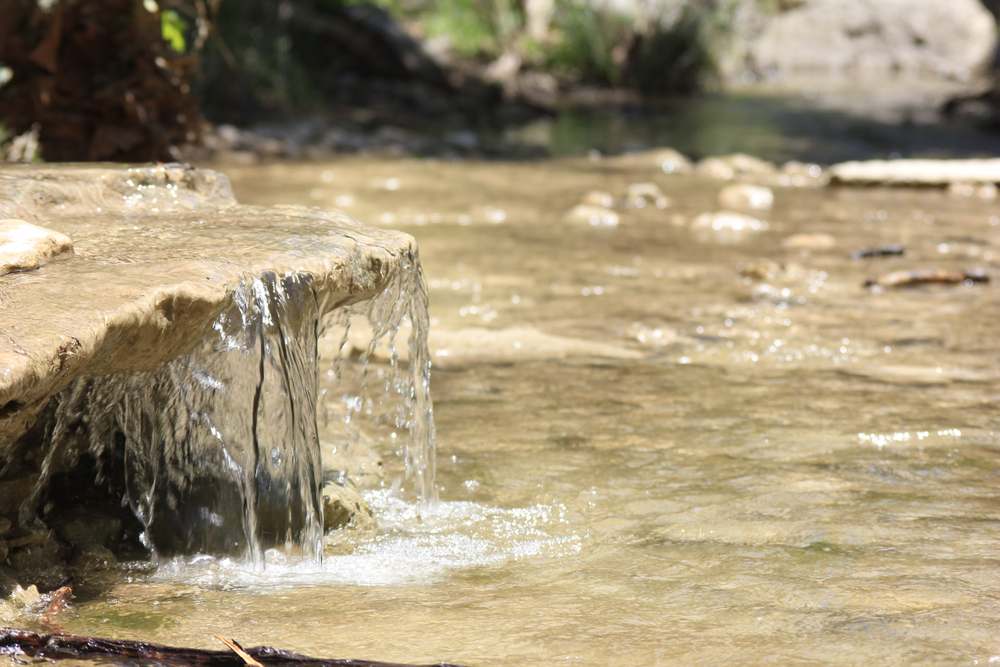 Running water over a flat limestone rock in a shallow river in the daylight at St. Edward