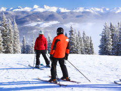 Two skiers in red jackets survey the mountains at Breckenridge Ski Resort, one of the best ski resorts close to Denver.
