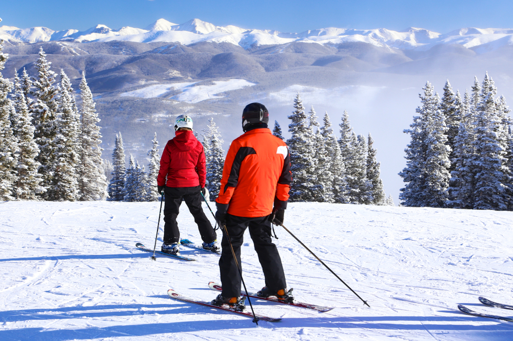 Two skiers in red jackets survey the mountains at Breckenridge Ski Resort, one of the best ski resorts close to Denver.