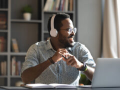 A remote worker smiles while working and listening to good music to work to.