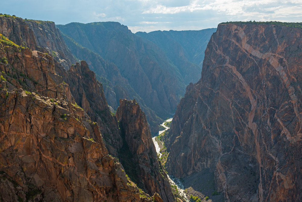 Steep granite cliffs of the Black Canyon of the Gunnison with the two dragons and the mysterious Gunnison River cutting through the rock in the valley, Colorado, USA.