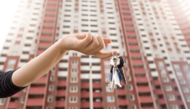 Hand holding keys with apartment building in the background
