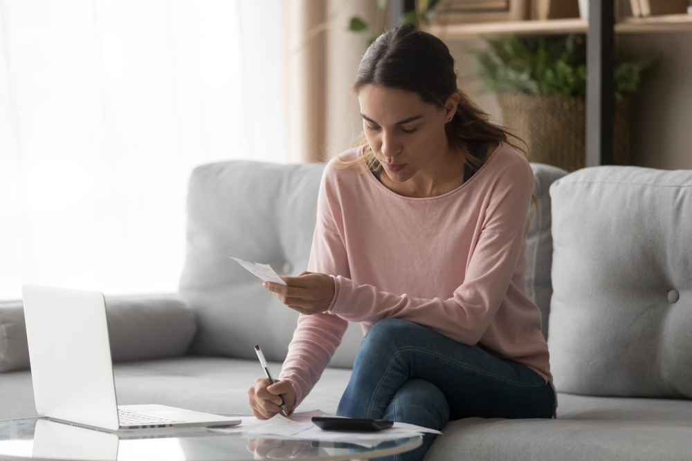 A woman makes a budget and calculates her rent as she figures out how much rent she can afford.