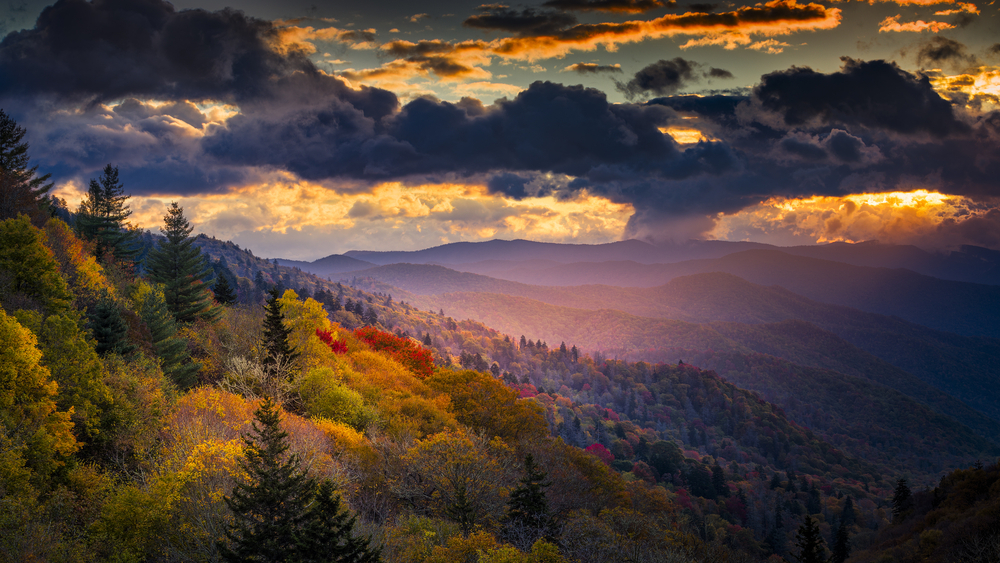 A single shaft of golden dawn sunlight illuminates autumnal ridges and valleys in Great Smoky Mountains National Park