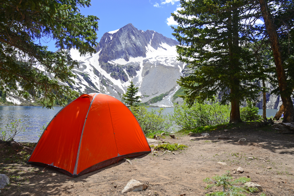 Camping tent in the Rocky Mountains with lake and snow capped peaks