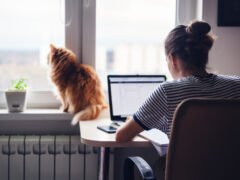 Young woman working in her home office with her cat