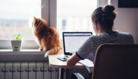 Young woman working in her home office with her cat