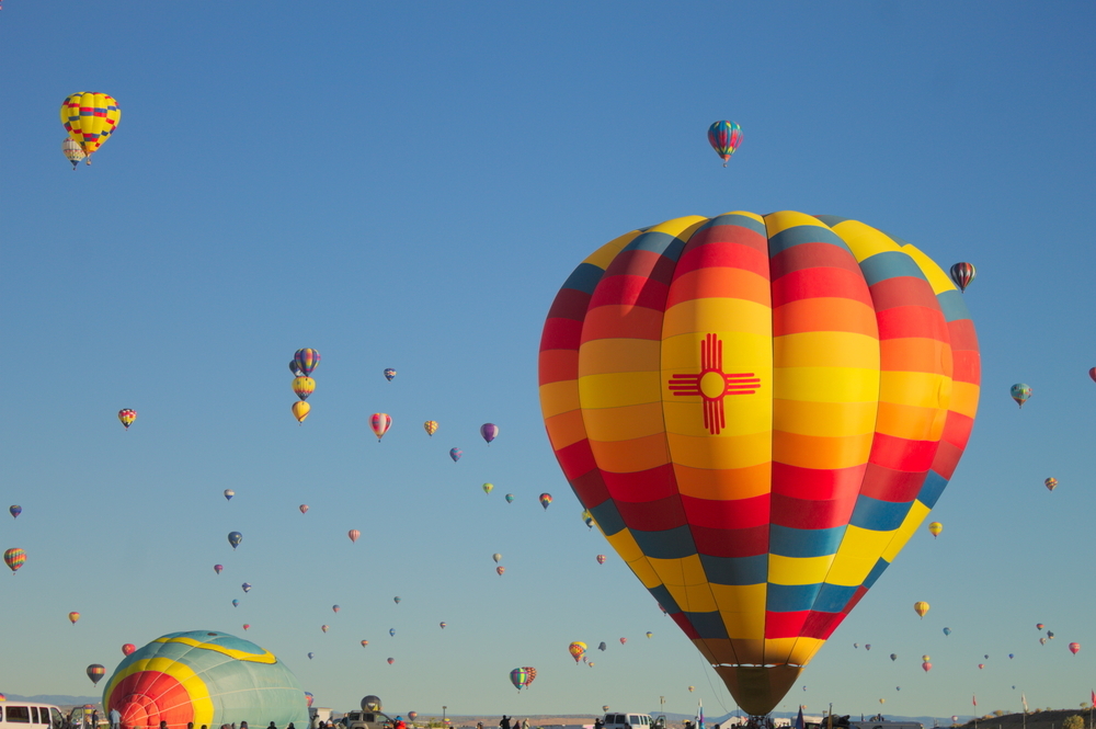 Large hot air ballon with zia sun symbol. Many hot air balloons in background. Albuquerque International Balloon Fiesta - Albuquerque, NM, USA.