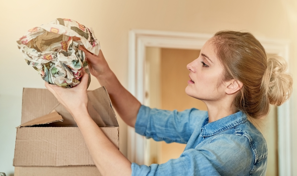 Making sure her valuables are snugly packed. Shot of a young woman unpacking a box at home.