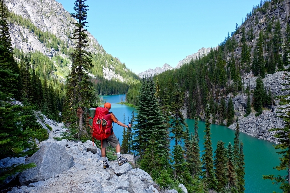 Man hiker by alpine lake. Nada lake, Enchantment Lakes basin, Leavenworth, Seattle, Washington state, USA .