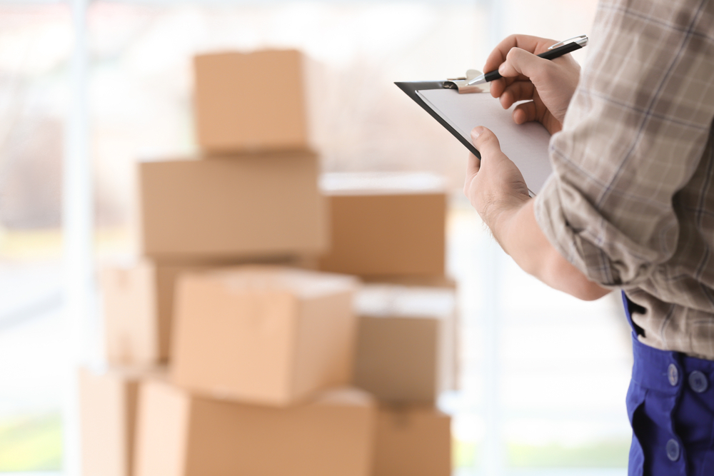Man holding clipboard on blurred boxes background Man holding clipboard on blurred boxes background