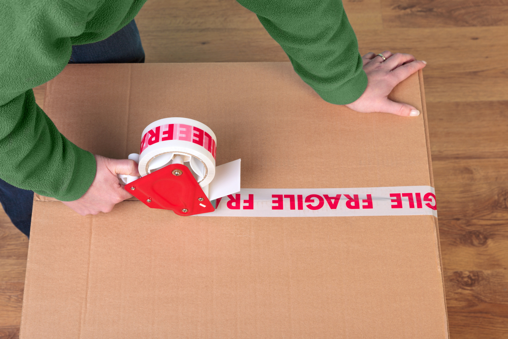 Photo of a womans hands taping up a cardboard box, can be used for removal or logistics related themes. Photo of a womans hands taping up a cardboard box, can be used for removal or logistics related themes.