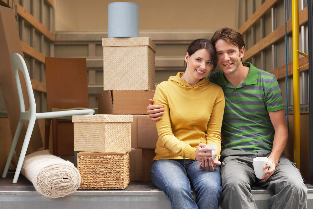 A couple sitting on the back of a moving truck, learning what they need to know to rent a U-Haul.