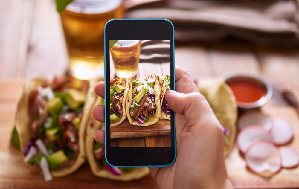 A diner using a phone to photograph the best Mexican food in Denver.