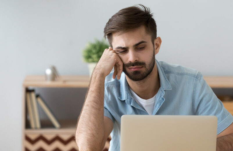 Man dealing with distractions on his laptop while working from home.