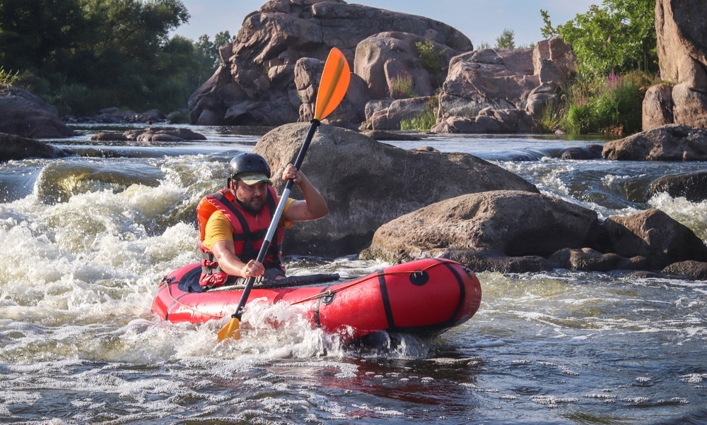 A man rowing inflatable packraft on whitewater of mountain river