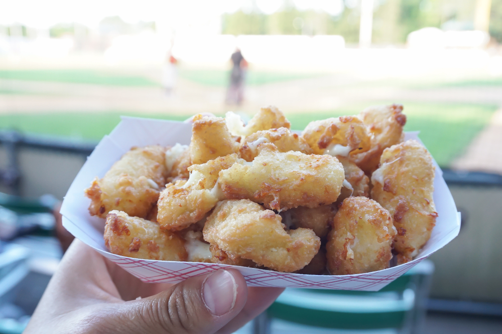 Cheese curds on a paper plate at a baseball game.