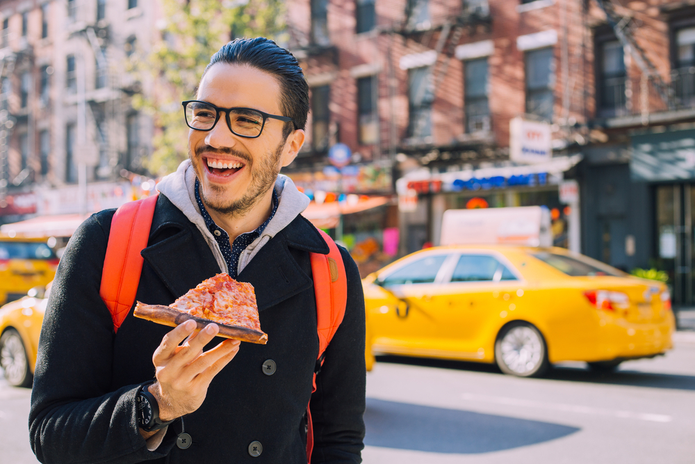 Man eating a pizza slice in New York