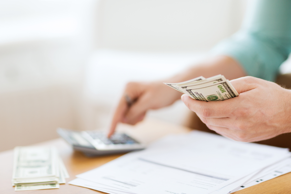 savings, finances, economy and home concept - close up of man with calculator counting money and making notes at home