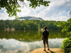 A man standing in front of a lake and Stone Mountain in Atlanta, Georgia