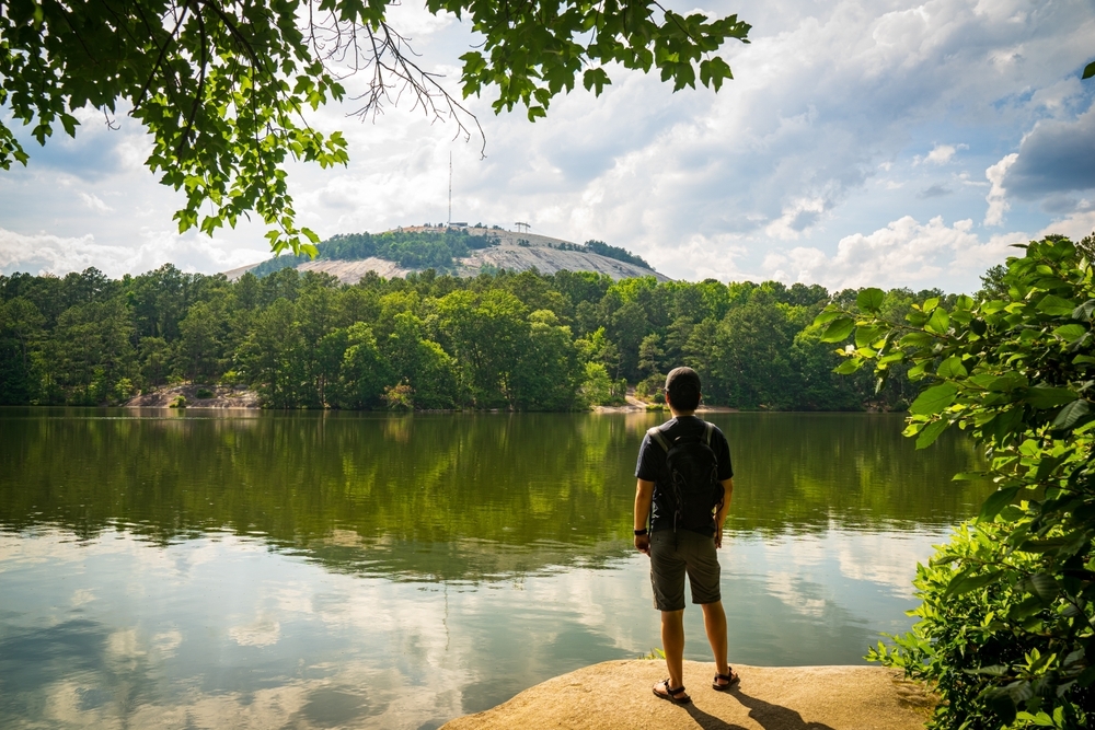 A man standing in front of a lake and Stone Mountain in Atlanta, Georgia